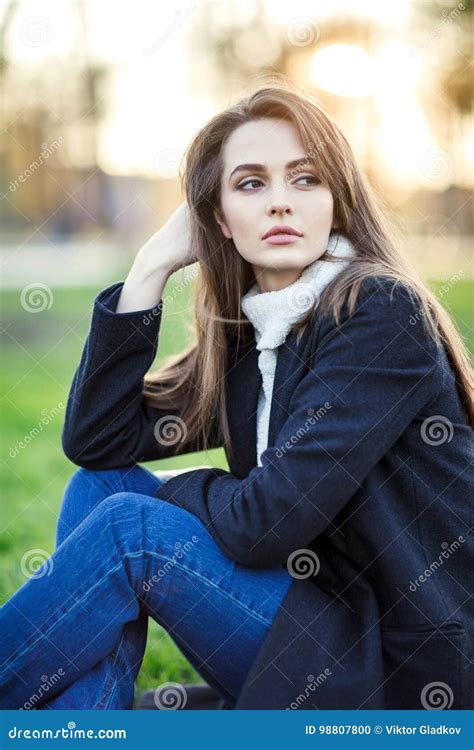 Young Beautiful Woman Sitting On A Grass In Sun Light On Sunset Stock