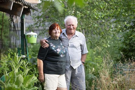 A beautiful very elderly couple hugs and looks at the camera at the ...