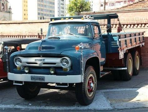 An Old Truck Parked On The Side Of The Road Next To Another One In