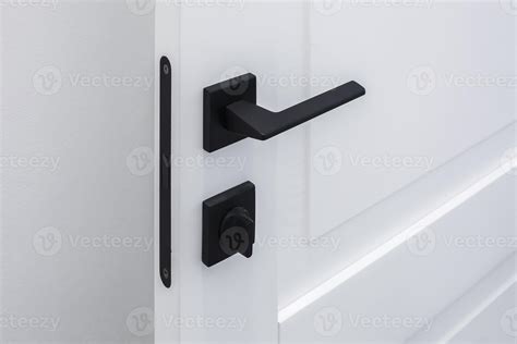 Modern black door handle on white wooden door in interior. Knob close
