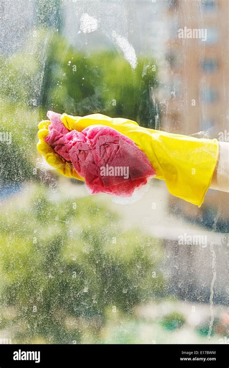 Hand In Yellow Rubber Glove Washing Window Glass By Soapy Water Stock