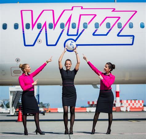 Three Women In Pink And Black Uniforms Holding Up A Soccer Ball On An