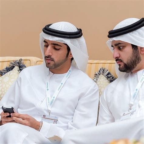 Two Men Sitting On A Couch Looking At Their Cell Phones