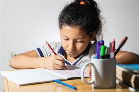 Niña estudiante latina haciendo su tarea muy concentrada trabajando
