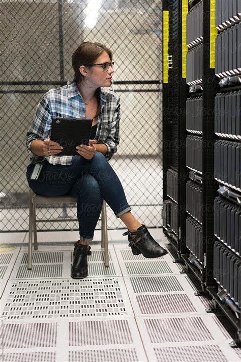 Server Room Technician Leans In To Look At Server By Stocksy