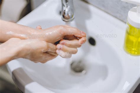 Woman Washes Hands With Liquid Soap At Home In The Bathroom Stock Photo