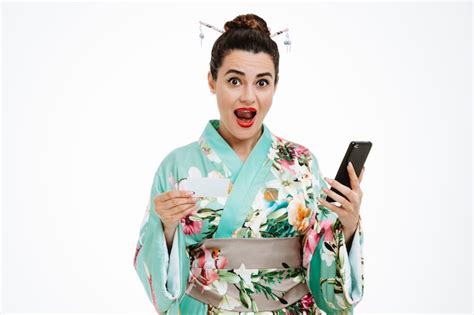 Jovem gueixa em quimono japonês tradicional segurando um smartphone e