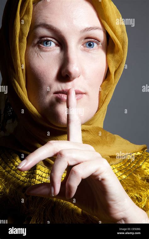 Woman Wearing Yellow Shawl With Finger Across Mouth For Silence Stock