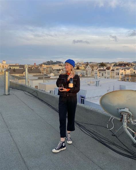 A Woman Standing On Top Of A Roof Next To A Satellite Dish In Front Of Her