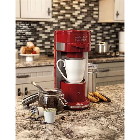 A Red Coffee Maker Sitting On Top Of A Kitchen Counter Next To Some Cups And Spoons