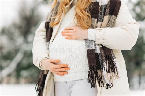 Pregnant Woman In Warm Winter Clothes Standing Outside On A Snowy