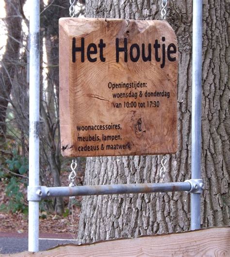 A Wooden Sign Hanging From The Side Of A Tree