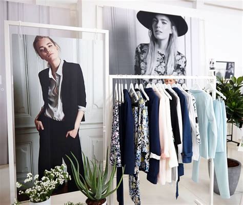 A Woman Is Standing In Front Of A Rack With Clothes On Hangers And A