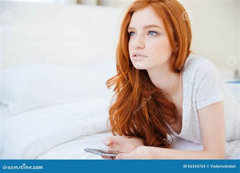 Femme Rousse Se Trouvant Sur Le Lit Avec Le Smartphone Photo Stock