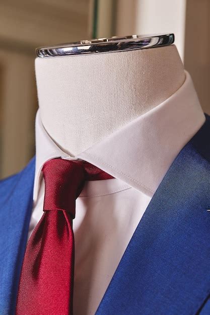 Maniquí con camisa blanca traje azul y corbata roja primer plano