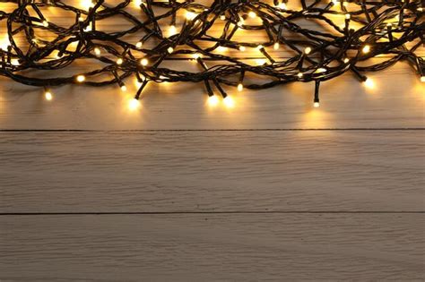 Premium Photo | Glowing festive lights on wooden background top view ...