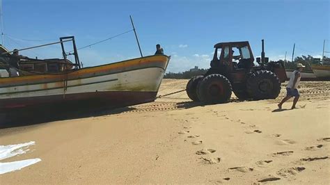 Barco de pesca retirado do mar por dois tratores no farol de São Tomé