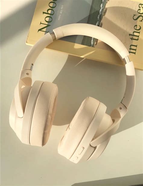 A Pair Of White Headphones Sitting On Top Of A Table Next To A Book