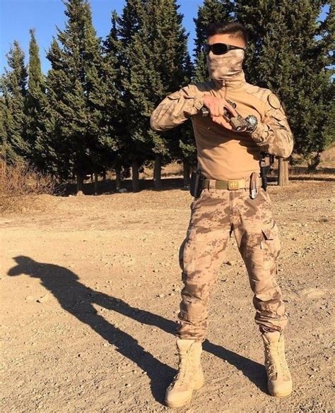 A Man In Camouflage Is Posing For The Camera With His Hands On His Hips