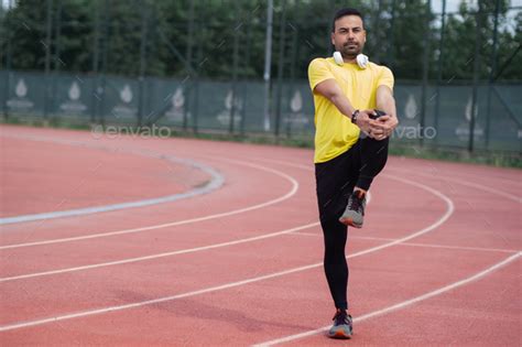 Dynamic Runner With Wireless Headphones Limbers Up Leg Muscles On