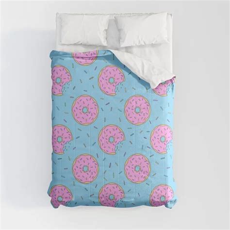 A Blue Bed With Pink Donuts And Sprinkles Printed On The Comforter