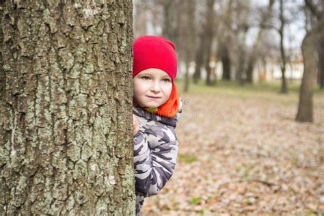 Little Boy Is Playing Hide And Seek Outdoors Portrait Of A Cute Little