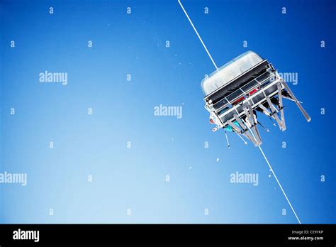 Ski Lift Carrying Unrecognizable Skiers Up To The Clear Blue Sky Stock