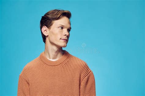 Cute Handsome Guy In An Orange Sweater Stands On A Blue Background