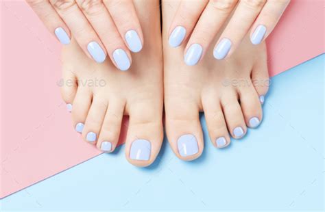 Female Hands And Feet With Manicure And Pedicure On A Blue And Pink