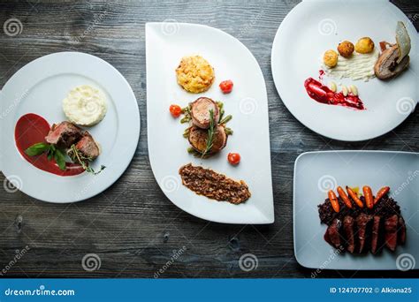 Wooden Table Topped With White Plates With Different Types Of Food In