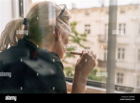 Mature Woman Smoking E Cigarette At Home Near The Window Caucasian 40 50 Years Old Female