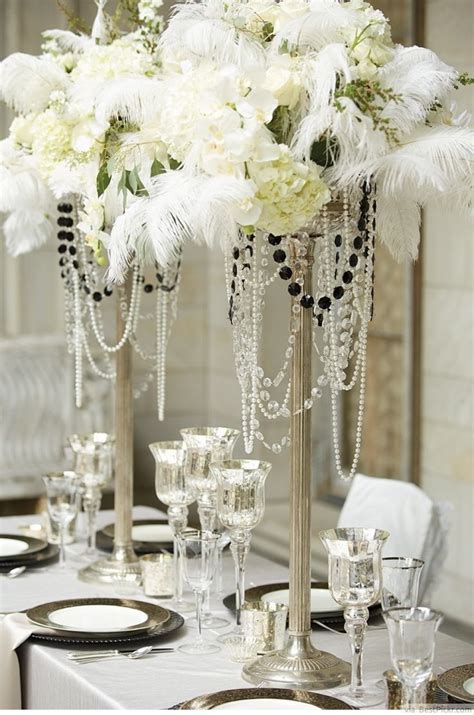 The Table Is Set With White Flowers And Silver Candlesticks Which Are