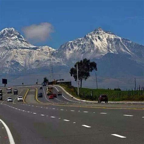 A Highway With Mountains In The Background And Cars Driving On It S Side