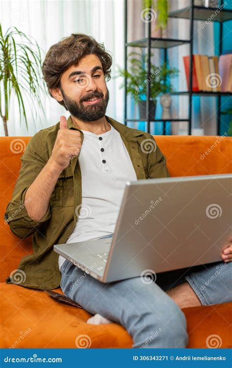 Man Sitting On Home Couch Looking At Camera Making Video Conference Call With Friends Or