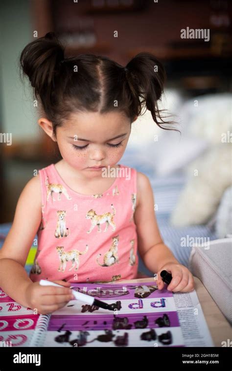 Una niña de cuatro años está coloreando en las letras de un libro