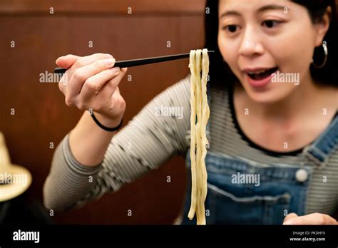 Pretty Woman Smiling And Eating Japanese Udon Happily In A Ramen Shop