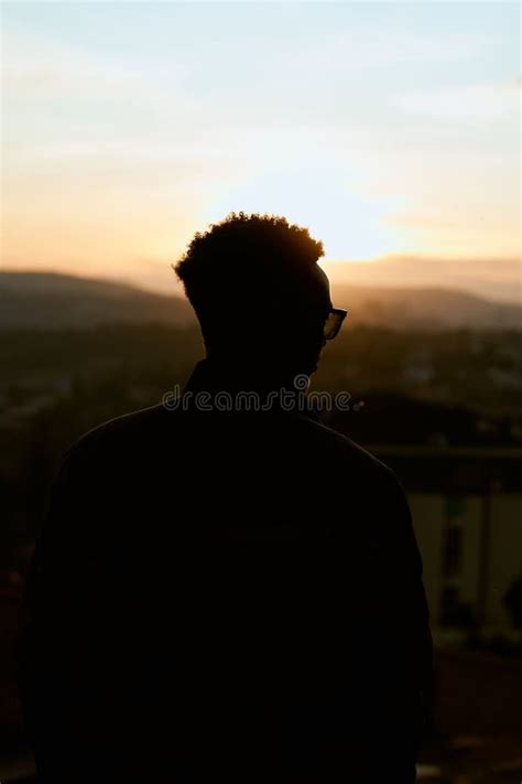 Toma Vertical De Una Silueta De Un Hombre Mirando La Puesta De Sol Foto