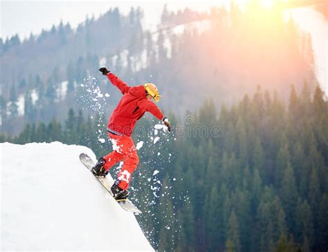 Male Snowboarder Jumping On The Top Of The Snowy Hill With Snowboard