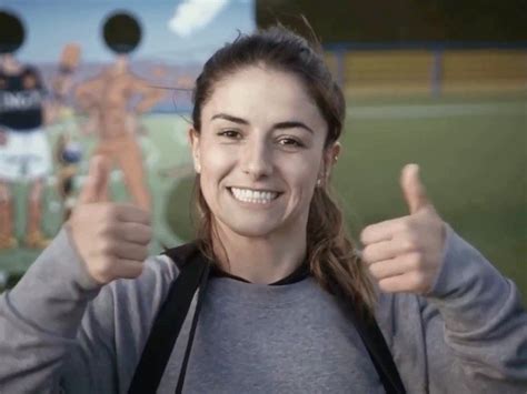 A Woman Giving The Thumbs Up Sign In Front Of A Wall With People On It