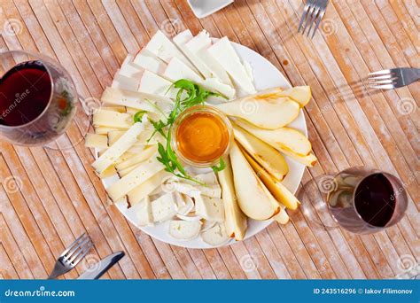 Plato Con Diferentes Tipos De Queso Y Taza De Miel Foto De Archivo