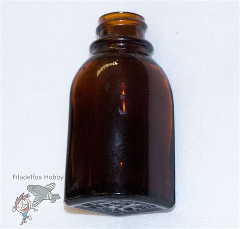 A Brown Glass Bottle Sitting On Top Of A White Table