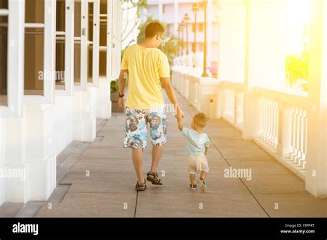 Back View Of Father And Son Holding Hands Walking In Sunset Parent And