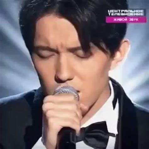 A Man In A Tuxedo Singing Into A Microphone