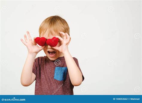 Cute Playful Boy Hiding His Eyes Behind Knitted Red Hearts Isolated On