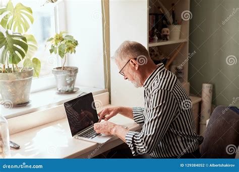 Mature Bearded Man Working From Home With Laptop Sitting At Desk Near