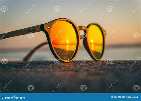 Un Par De Gafas De Sol En La Playa Con El Reflejo De La Puesta De Sol