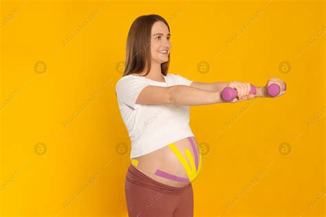 Pregnant Woman With Kinesio Tapes On Her Belly Doing Exercises Against