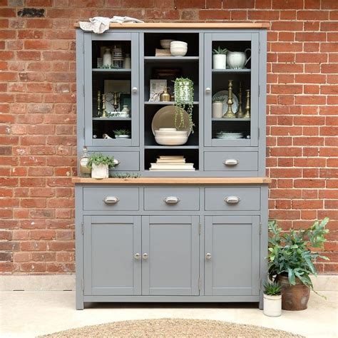 A Grey China Cabinet With Glass Doors And Drawers In Front Of A Red