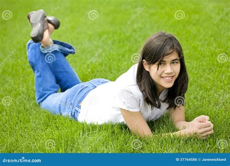 Menina Do Jovem Adolescente Que Encontra Se Na Grama Verde Relaxando