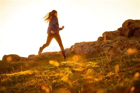 Young Woman Running On Rocky Mountain Trail At Sunset Active Lifestyle